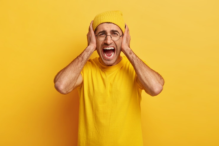 Free Photo depressed fed up stressful man looses temper, yells and screams loudly, covers ears