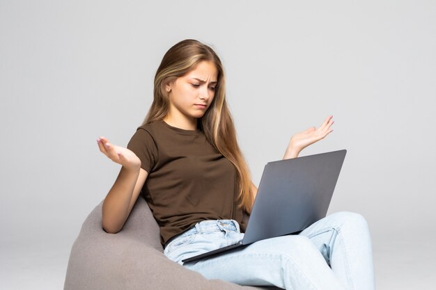 Depressed and frustrated woman working with computer laptop desperate in work isolated on white wall . Depression