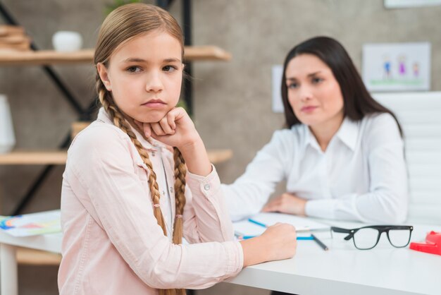 彼女の女性心理学者の前に座って意気消沈した少女