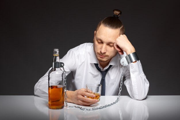 Depressed man spending time with a bottle of whiskey