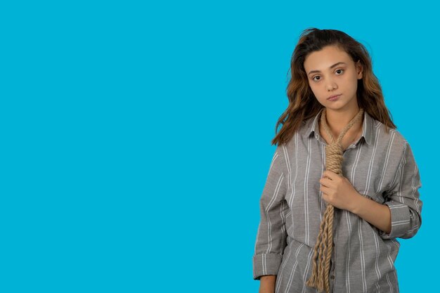 A depressed young girl put a rope around her neck and looking at camera. High quality photo