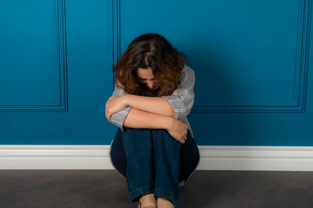 Depressed young girl sitting on the floor and crying. High quality photo