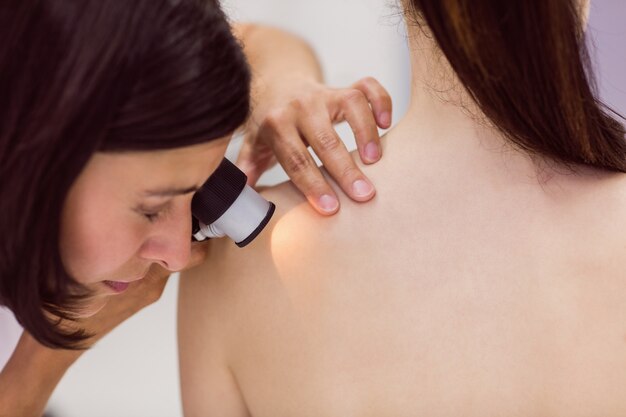 Дерматолог осматривает кожу пациента с помощью дерматоскопа