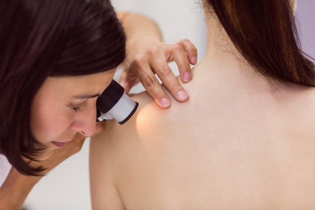 Dermatologist examining skin of patient with dermatoscope