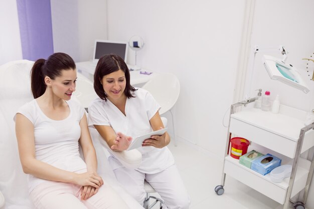 Dermatologist and female patient discussing on digital tablet