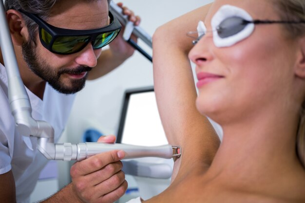 Dermatologist removing hair of patient armpit