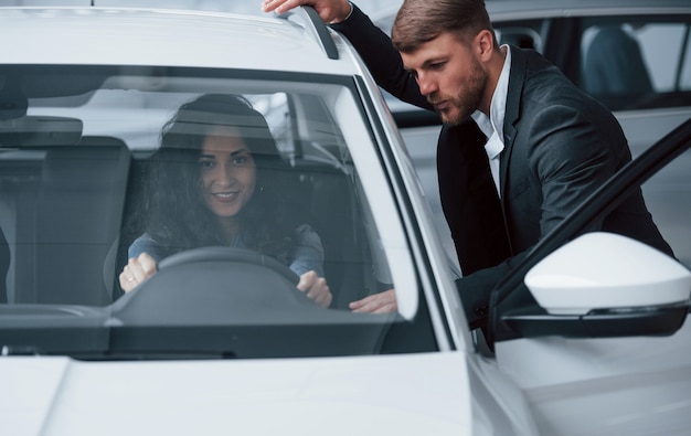 それについてどう思うか説明してください。女性客と自動車サロンでモダンなスタイリッシュなひげを生やした実業家