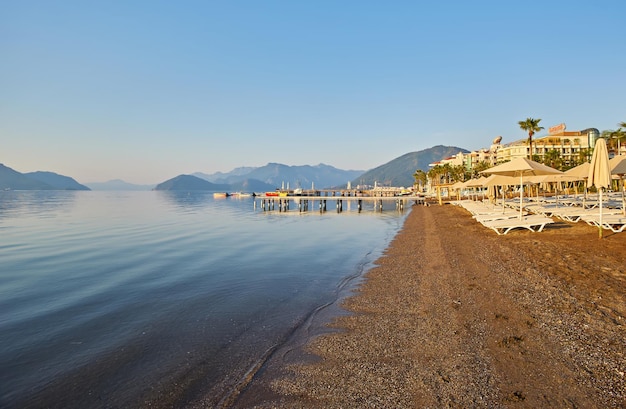 아침 햇살의 황량한 해변 새벽의 해변 텅 빈 선베드 사람들이 없는 해변 Marmaris