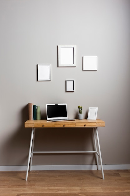 Free photo desk design with laptop and frames mock-up