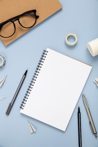 Desk elements on blue background with empty notebook