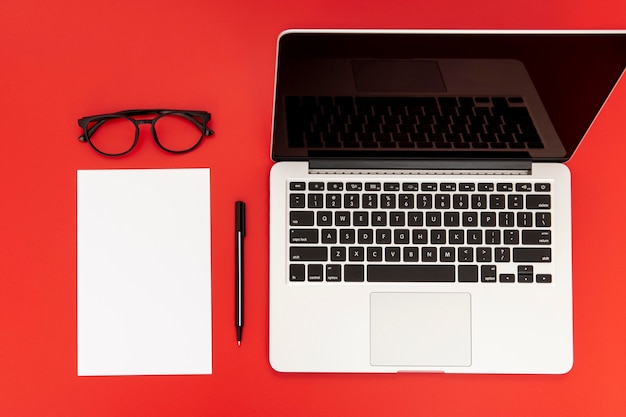 Desk elements with empty notebook on red background