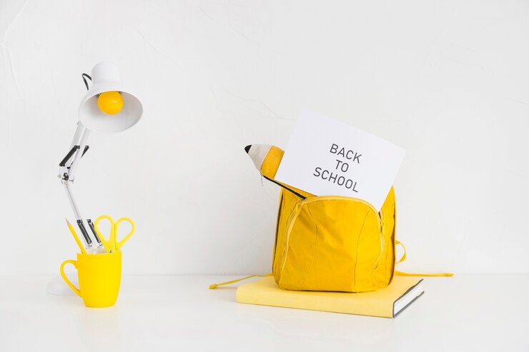 Free Photo desk with bright yellow backpack and pencil case