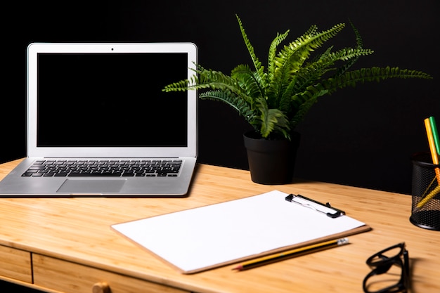 Free photo desk with laptop and clipboard mock-up