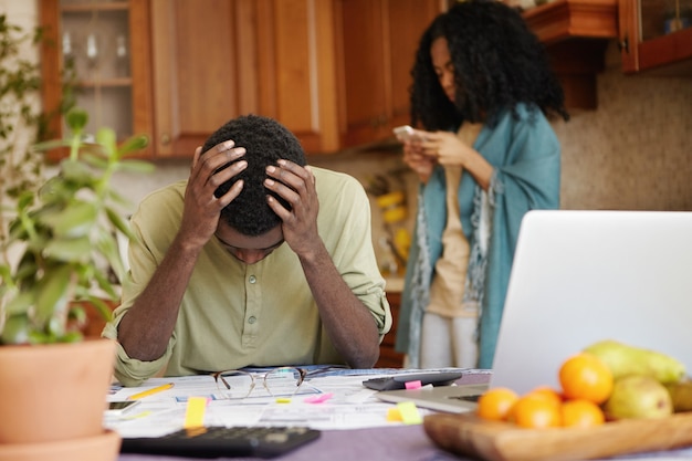 Desperate dark-skinned male touching head with both hands, feeling absolutely devastated