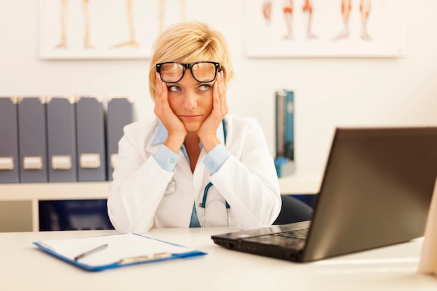 Foto gratuita medico femminile disperato seduto nel suo ufficio