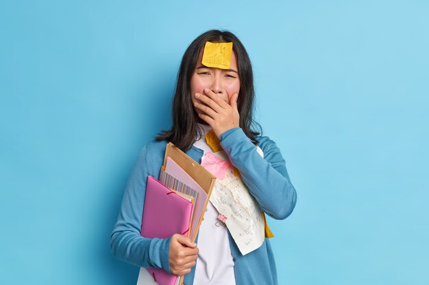 desperate female student cries unhappily covers mouth feels upset has sticker with graphic stuck on forehead has deadline for preparing to exams.