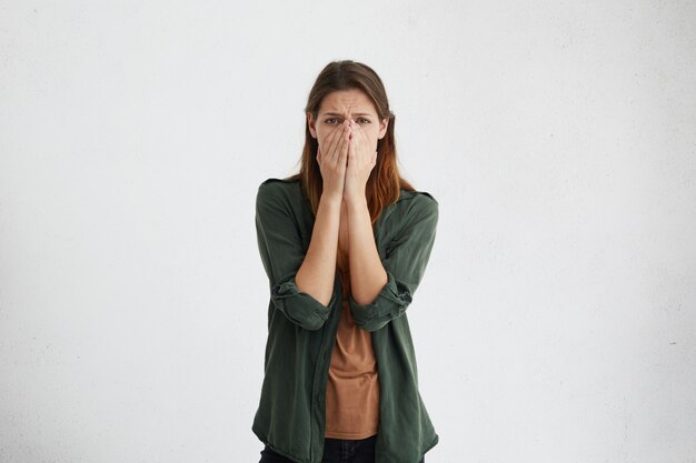 Desperate woman with dark eyes wearing brown T-shirt and green jacket going to cry