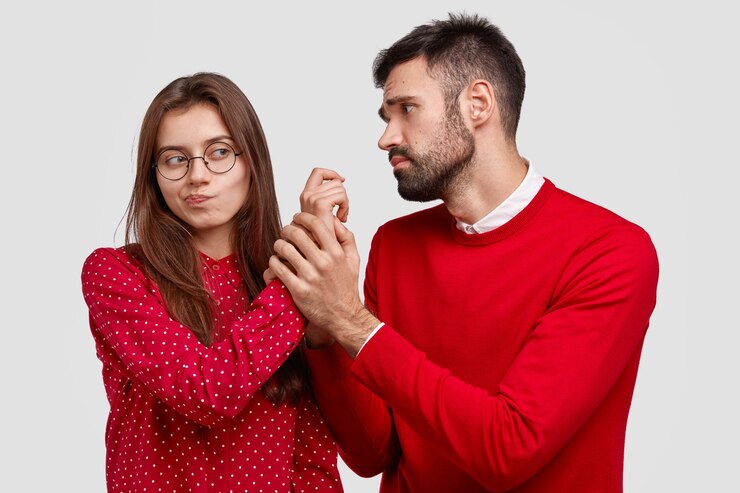 Free Photo desperate young caucasian man holds hand of girlfriend, looks with miserable expression, asks for forgiveness, feels guilty. couple have disagreement