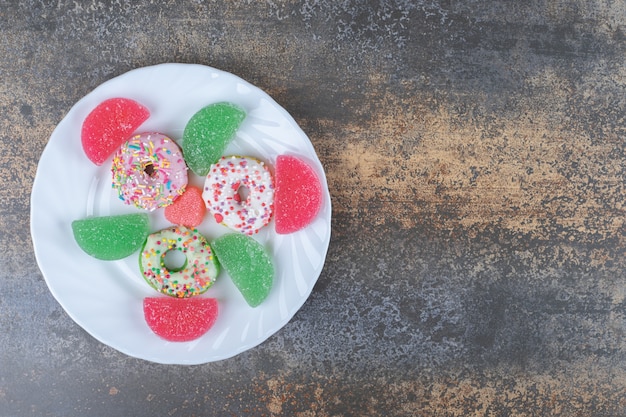 A dessert serving of donuts and marmelades on wooden surface