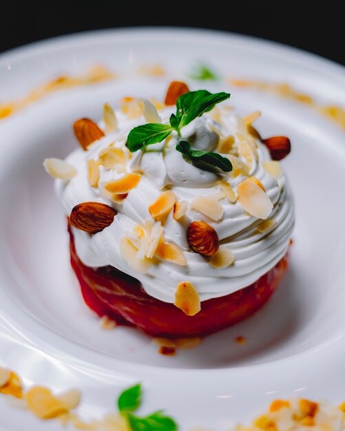 Dessert with cream and almond flakes on a white plate