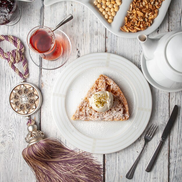 Dessert with tea, nuts in a plate on white wooden background, top view.