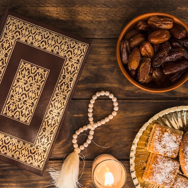 Десерты и свеча рядом с бусами и Кораном