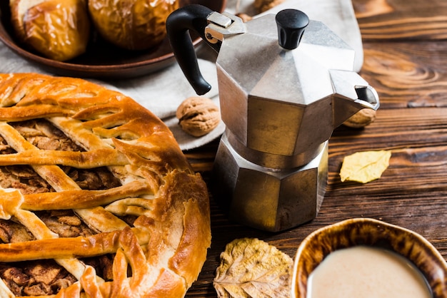 Desserts and coffee pot near leaves on table