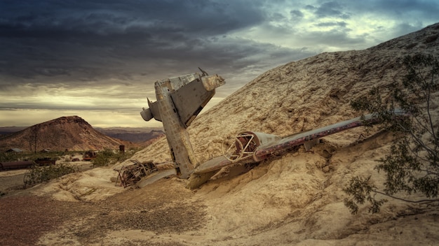 Destroyed gray plane on rock under gray skies