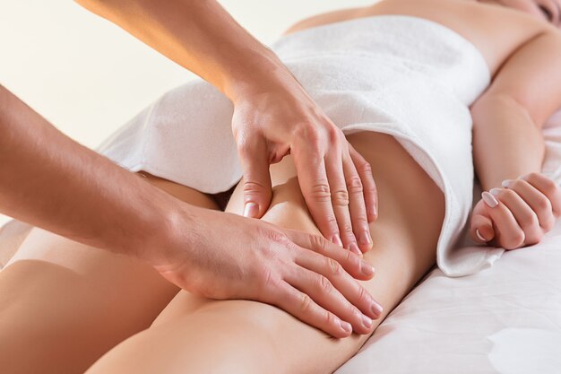 Detail of hands massaging human calf muscle.