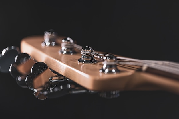 Free photo detail of a tuning post on the wooden headstock of an electric bass guitar.