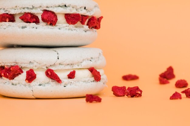 Detail of white macaroon with dried red berries on colored backdrop