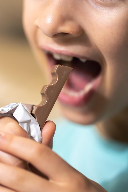 Foto gratuita una foto dettagliata di una ragazza che morde una barretta di cioccolato