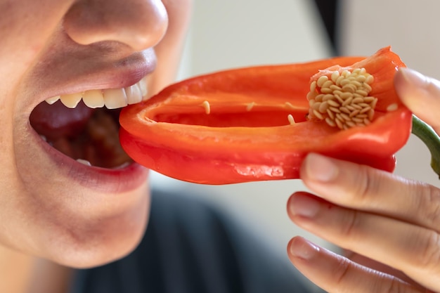 Detailed shot of a woman bites red bell pepper