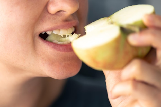 Free photo detailed shot of a woman eats piece of fresh apple