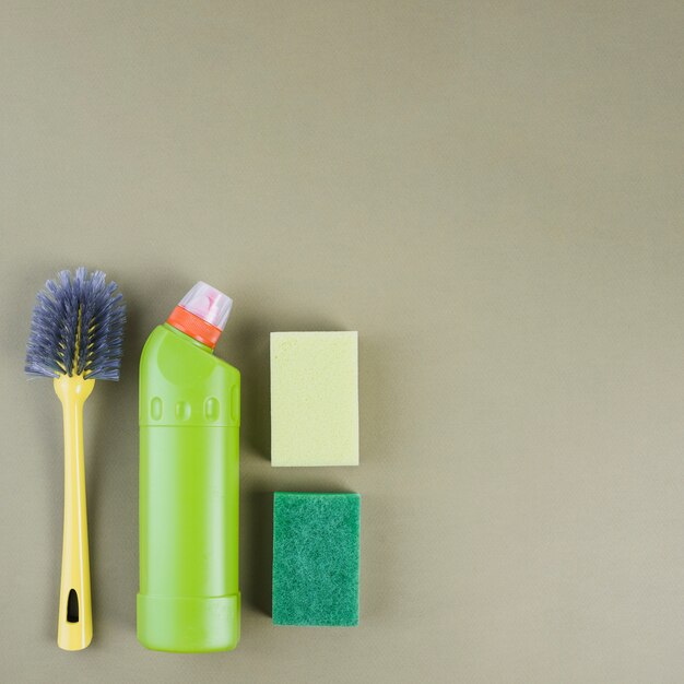 Detergent bottle, brush and sponge on colored background