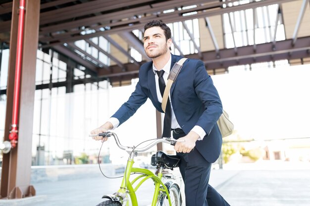 Determined manager in elegant suit riding vintage bicycle in city