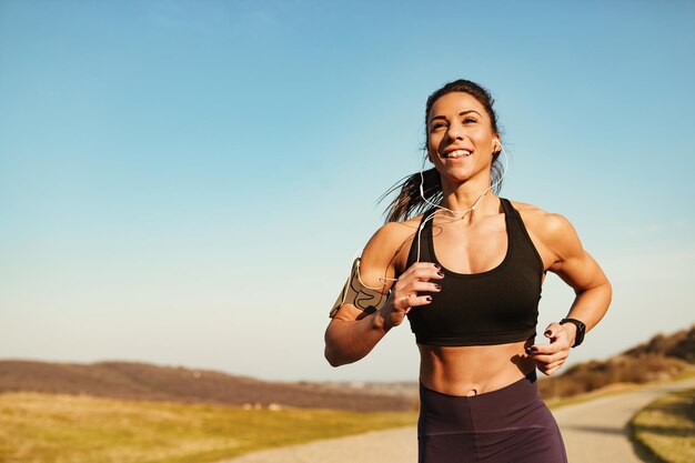 自然の中で運動しながら走っている決心した筋肉のビルド女性コピースペース