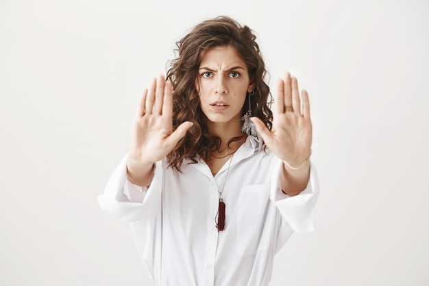 Determined serious woman showing stop gesture, extending her hands to prohibit action