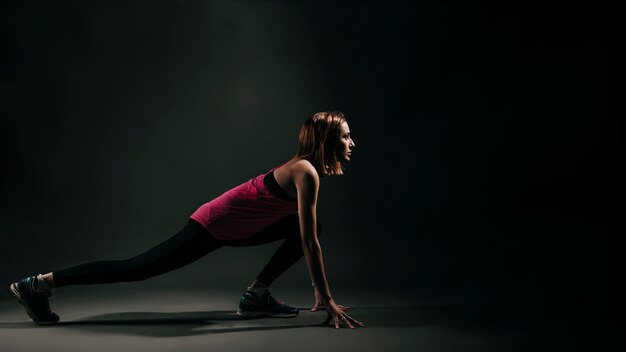 Determined sportswoman stretching on black