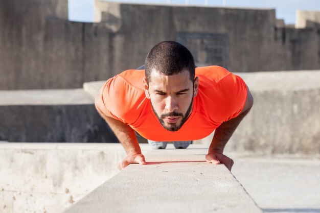 Determined Sporty Man Doing Push-ups on Parapet