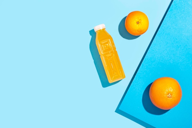 플라스틱 병에 있는 해독 주스, 파란색 배경에 오렌지. 평면도, 평면도.