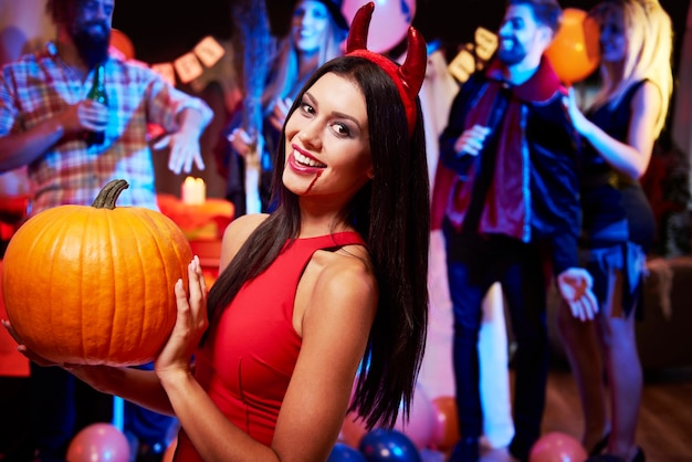 Free photo devil lady posing near big pumpkin