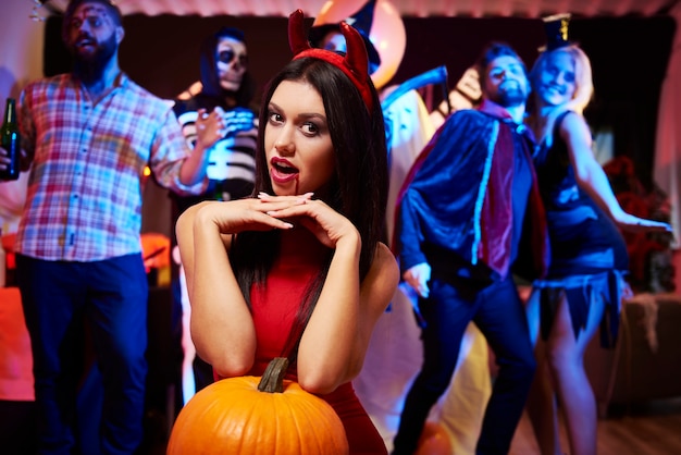 Devil lady posing near big pumpkin