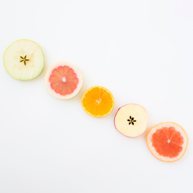 Free photo diagonal row of apple slices; grapefruit and orange slices on white background