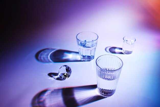 Diamond with glasses of drinks on colorful backdrop with shadow