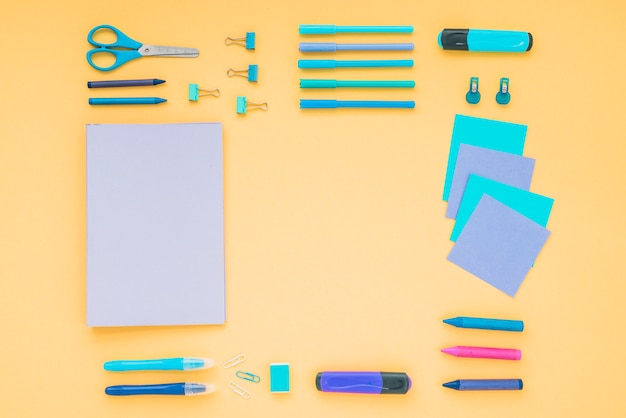 Free photo diary; crayons; scissor with office stationery arranged on orange backdrop