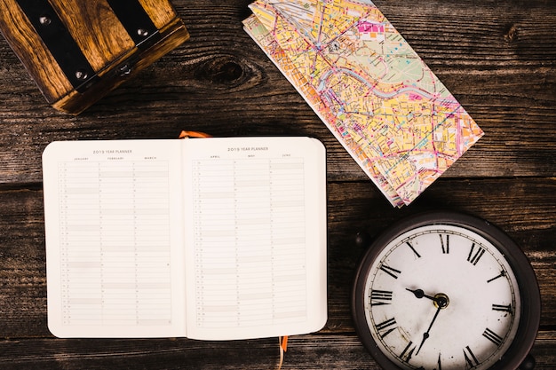 diary, map and clock on wooden plank