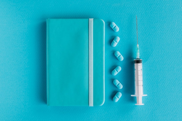 Free photo diary; pills and syringe on blue surface