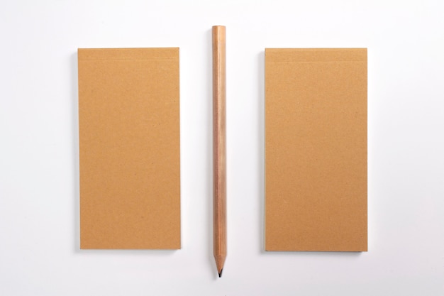 空白の段ボールのハードカバーと白で隔離される木製の鉛筆の日記。