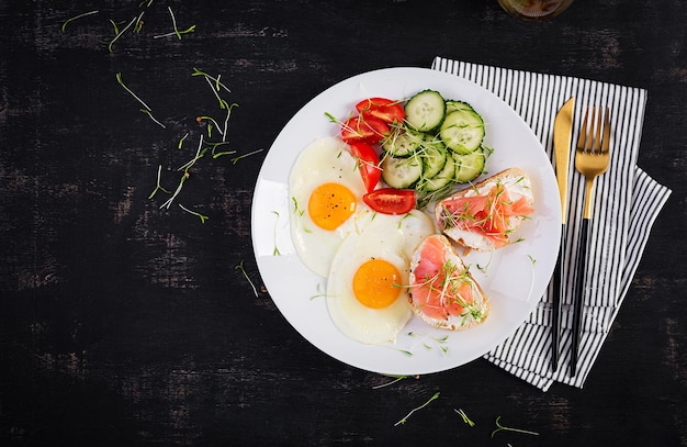 Диетический завтрак. жареные яйца и бутерброды с соленым лососем и свежим салатом. вид сверху, сверху